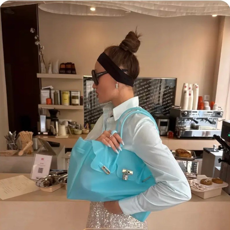 Sac Jelly Firkin bleu porté au bras dans un café